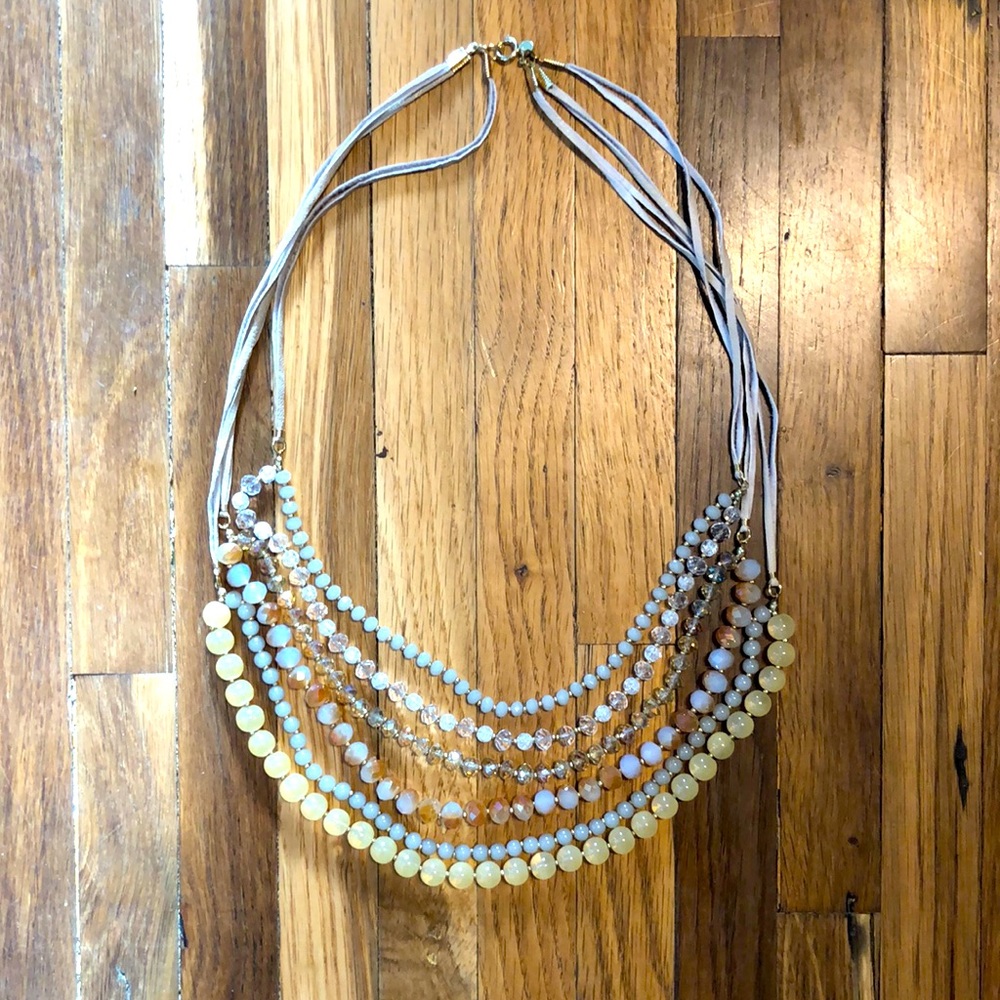 Neutral color long, dangly beaded necklace with leather strings.